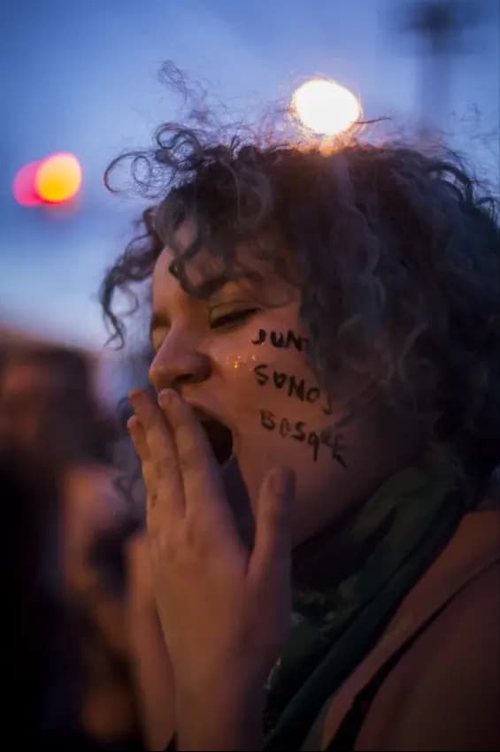 Mujer en manifestación con texto escrito en la cara
